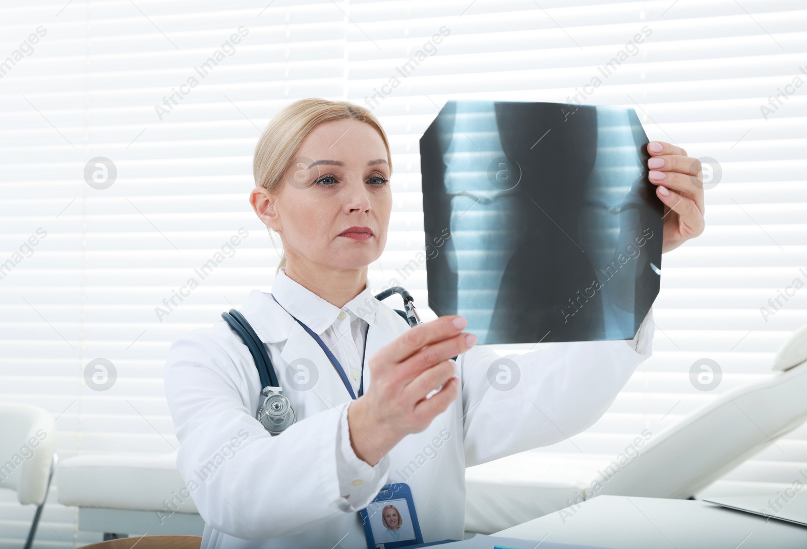 Photo of Doctor examining x-ray image of knee at table in clinic