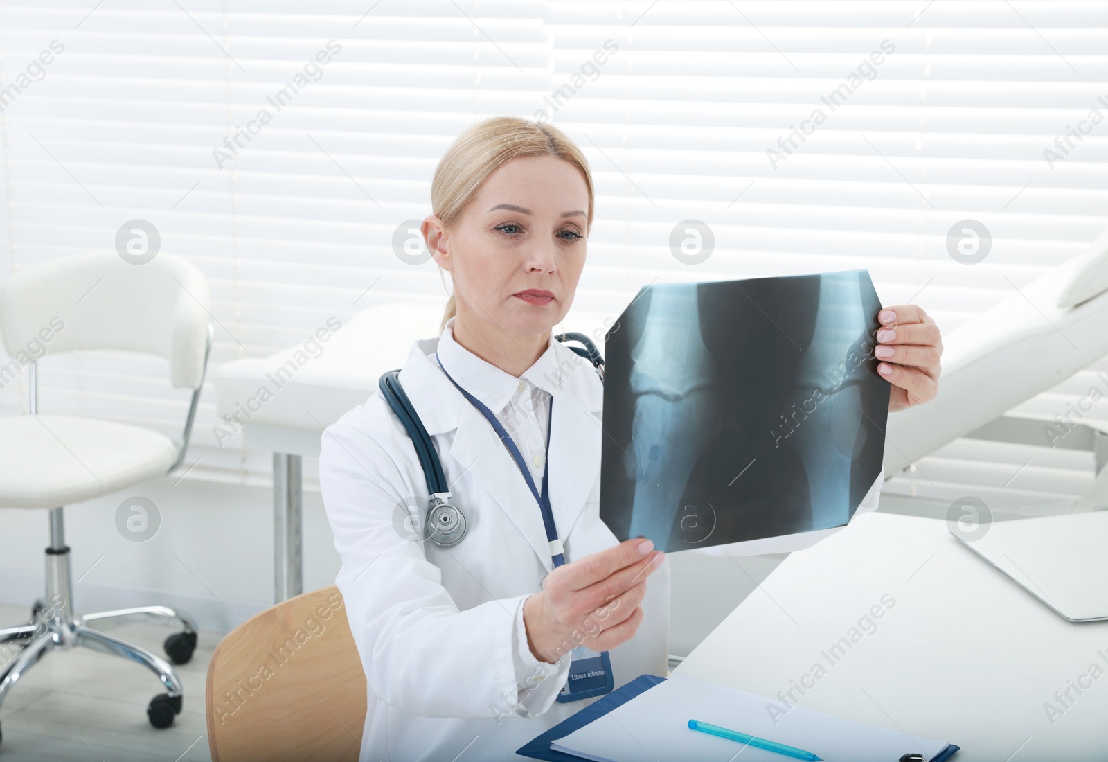 Photo of Doctor examining x-ray image of knee at table in clinic