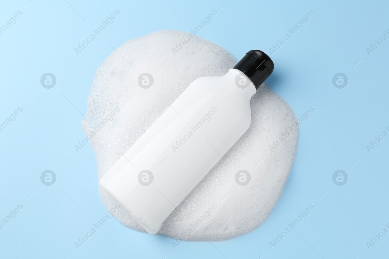 Photo of Bottle of cosmetic product with foam on light blue background, top view