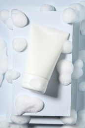 Photo of Tube of cosmetic product with foam on white background, top view