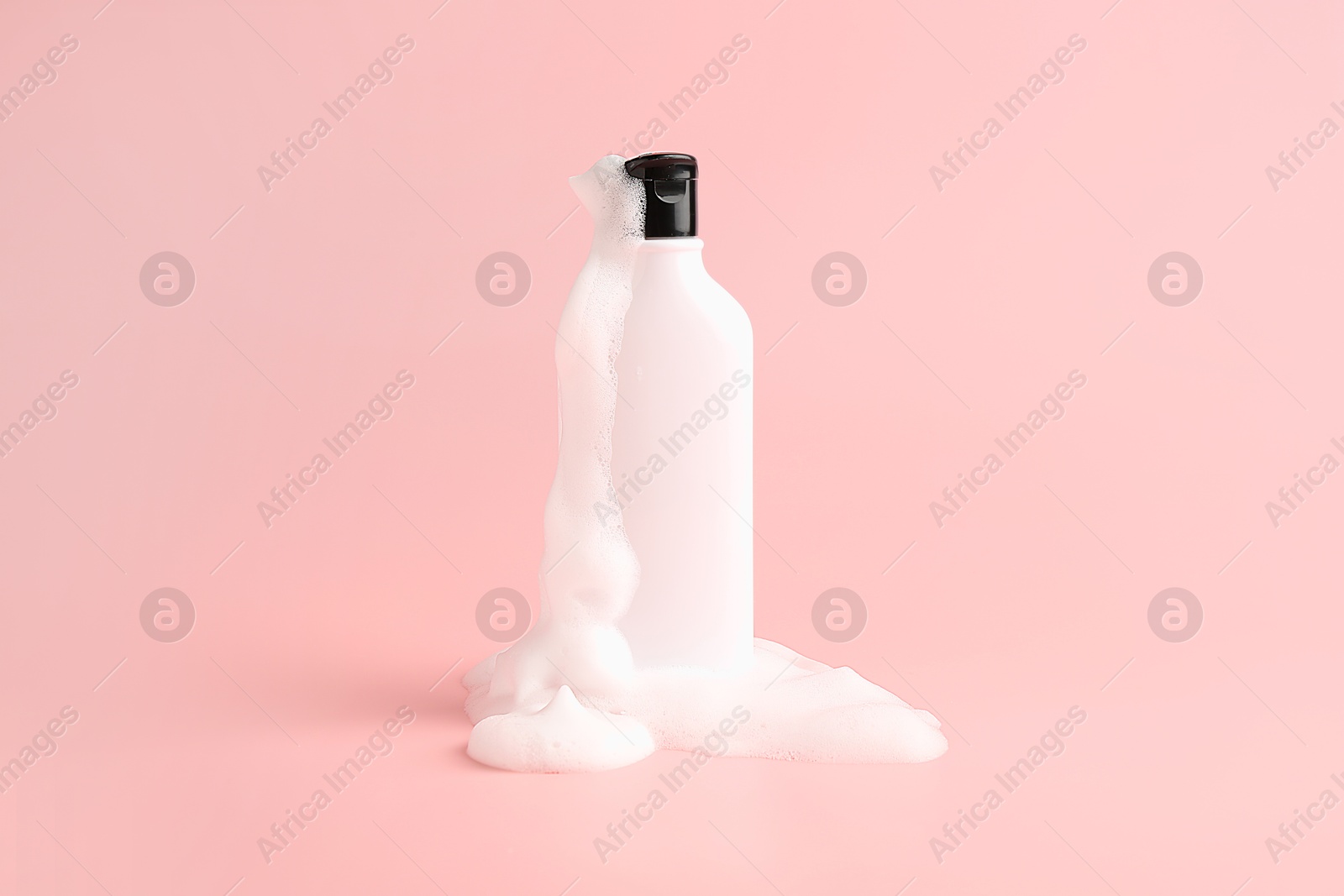 Bottle of cosmetic product with foam on pink background Photo of Bottle of cosmetic product with foam on pink background