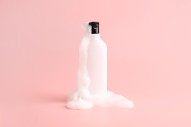 Photo of Bottle of cosmetic product with foam on pink background