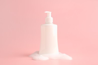 Bottle of cosmetic product with foam on pink background