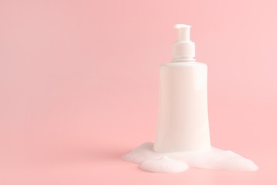 Bottle of cosmetic product with foam on pink background, space for text