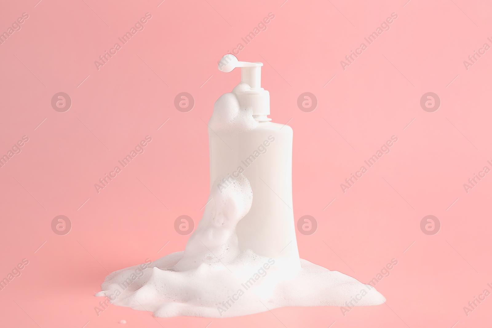 Photo of Bottle of cosmetic product with foam on pink background