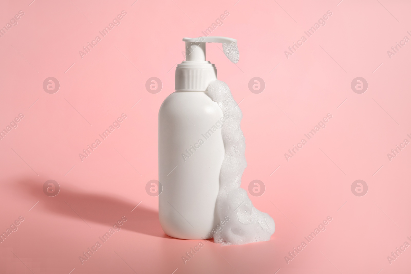 Photo of Bottle of cosmetic product with foam on pink background