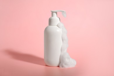 Bottle of cosmetic product with foam on pink background