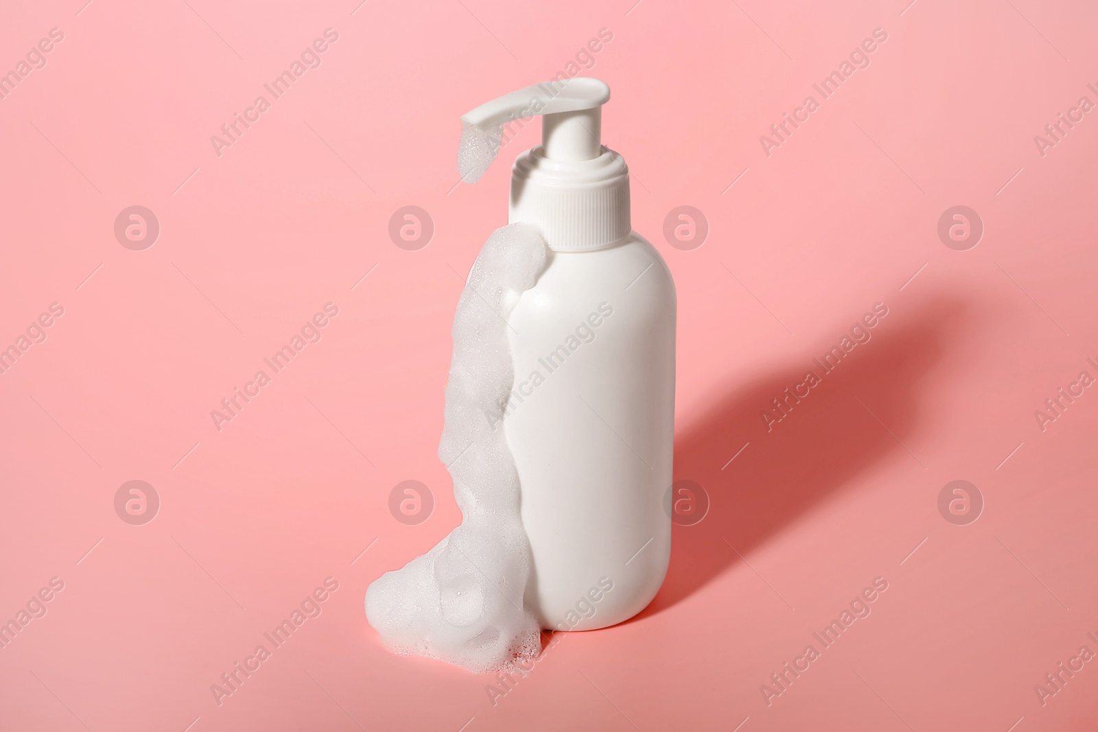 Photo of Bottle of cosmetic product with foam on pink background