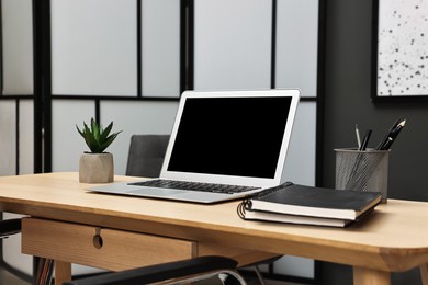 Photo of Comfortable workplace with modern laptop on wooden table indoors