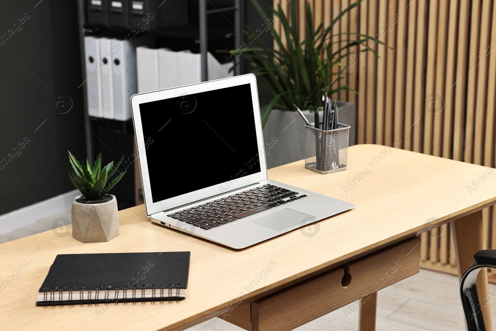 Photo of Comfortable workplace with modern laptop on wooden table indoors