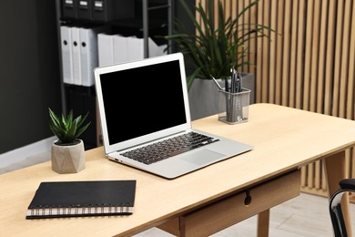 Photo of Comfortable workplace with modern laptop on wooden table indoors