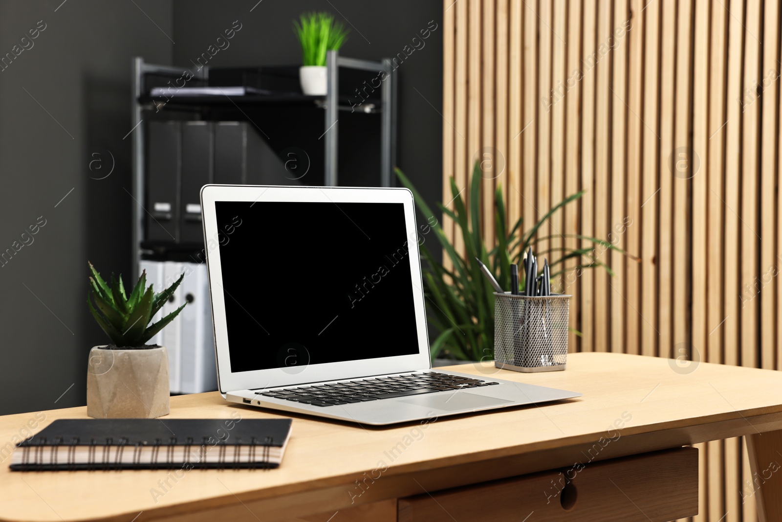 Photo of Comfortable workplace with modern laptop on wooden table indoors