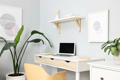 Photo of Comfortable workplace with modern laptop on white table indoors