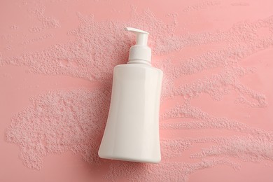 Bottle of cosmetic product with foam on pink background, top view