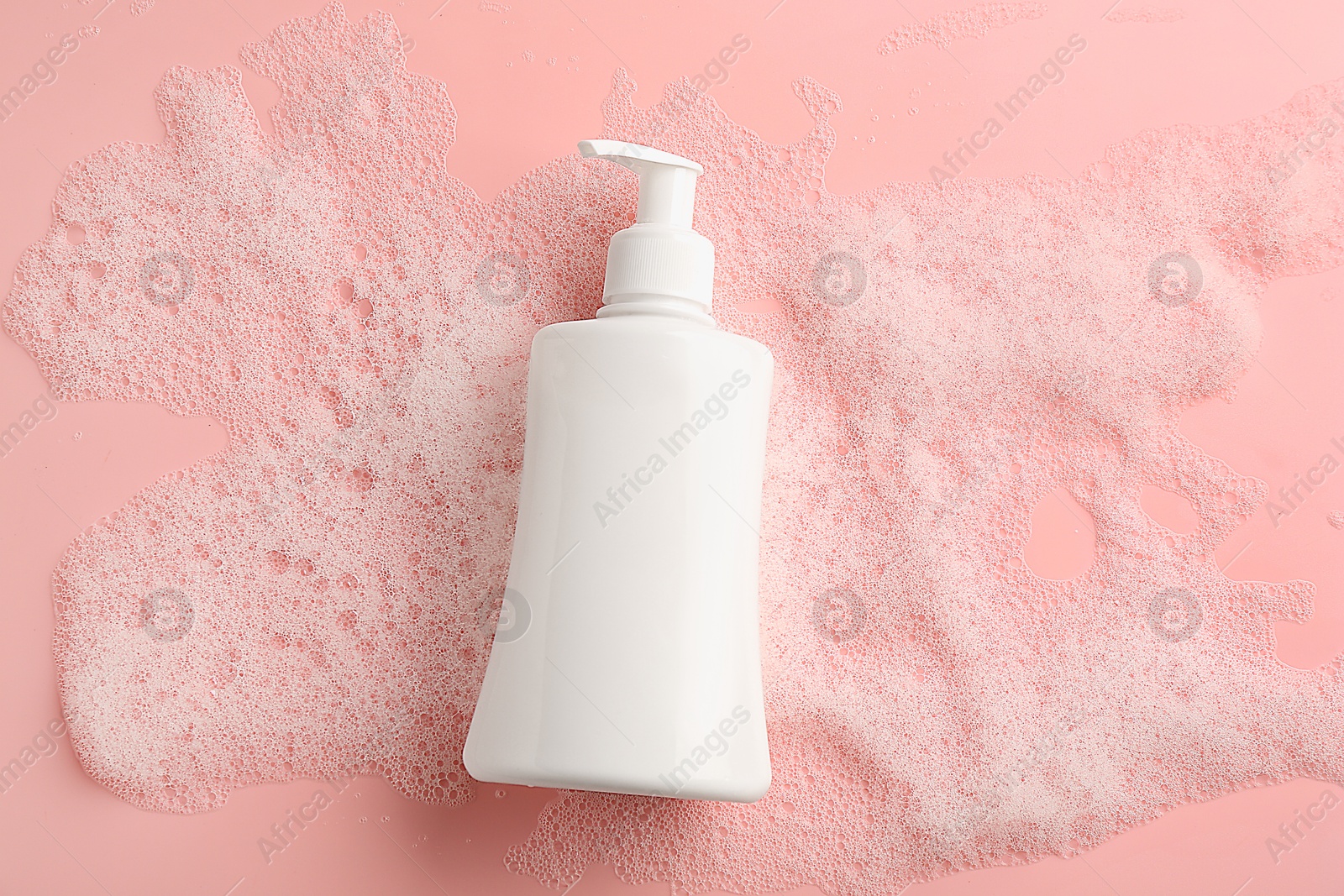 Photo of Bottle of cosmetic product with foam on pink background, top view