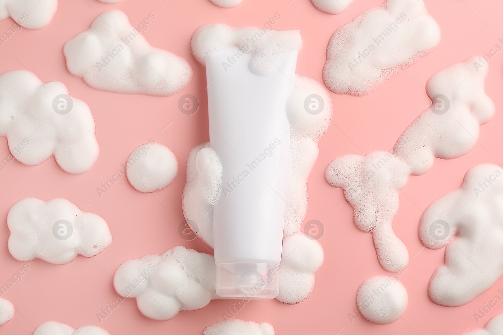 Photo of Tube of cosmetic product with foam on pink background, top view