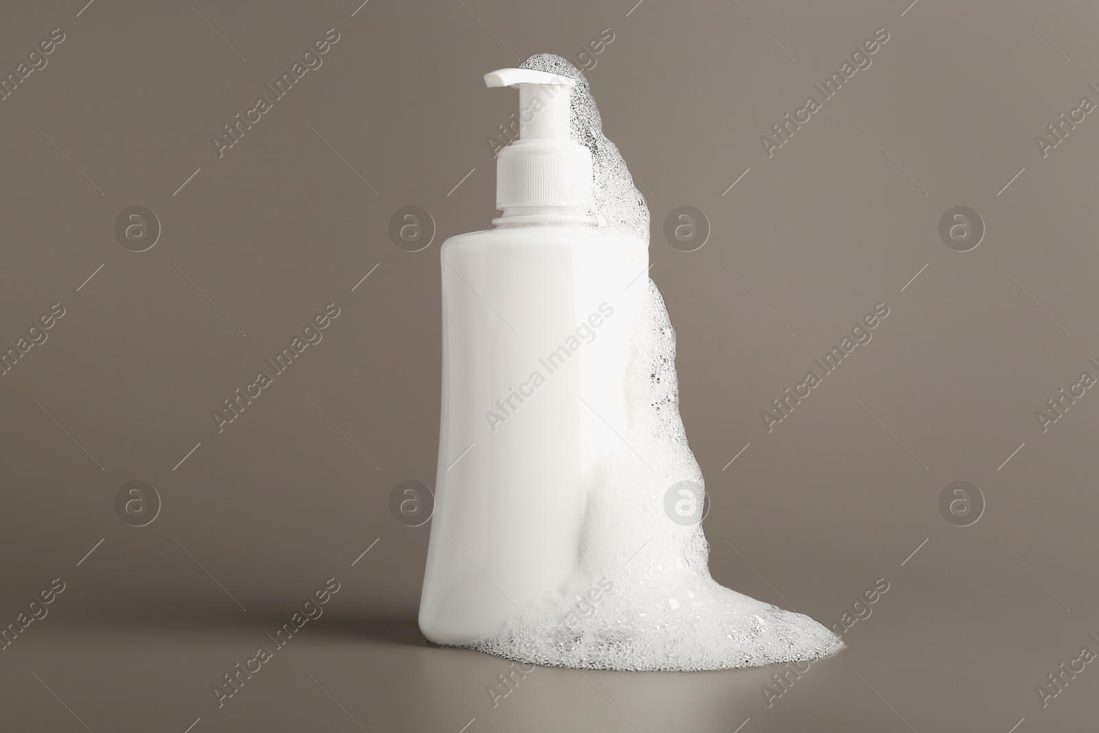 Photo of Bottle of cosmetic product with foam on grey background