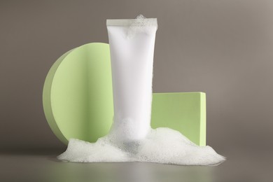 Presentation of cosmetic product in tube with foam on grey background