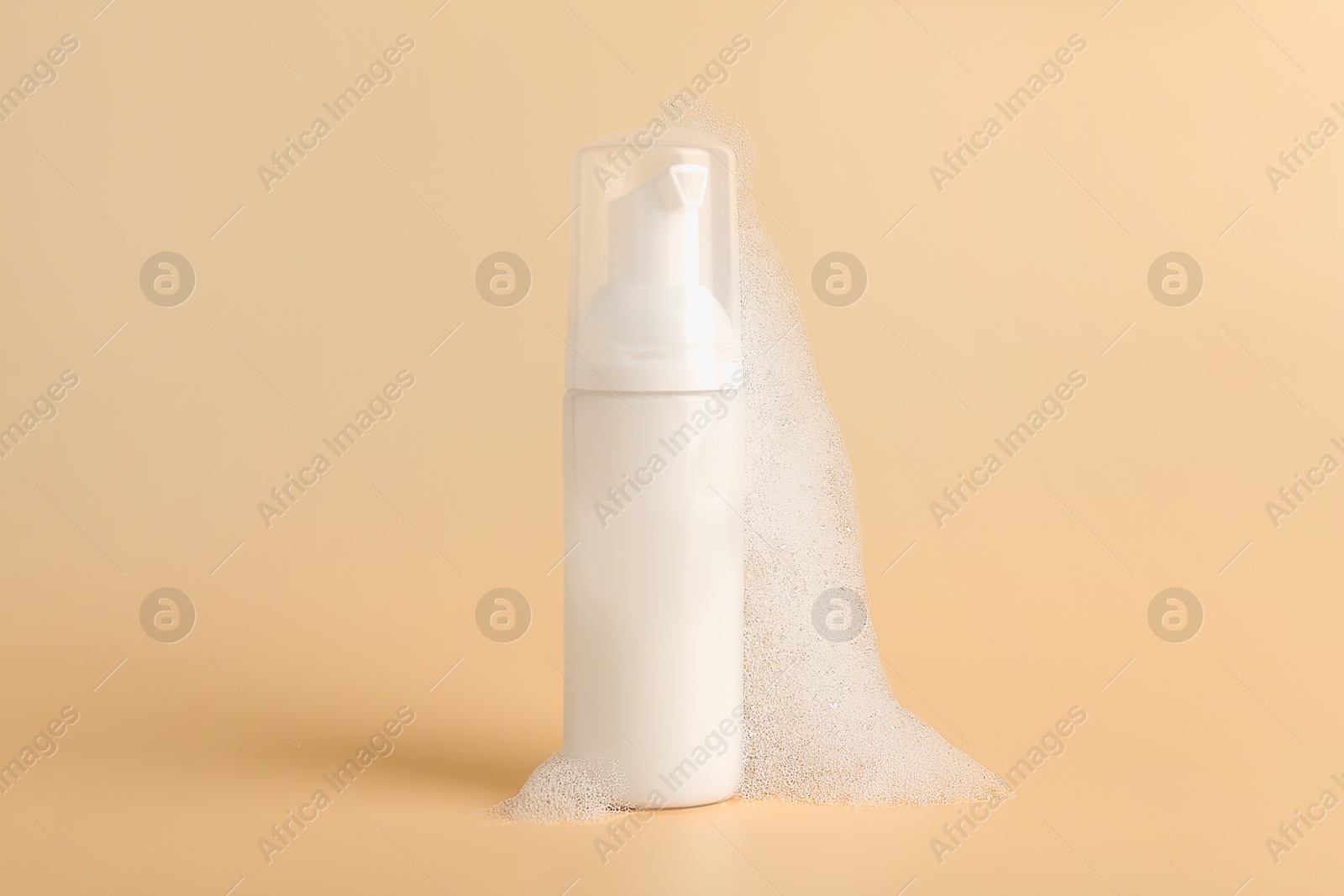 Photo of Bottle of cosmetic product with foam on beige background