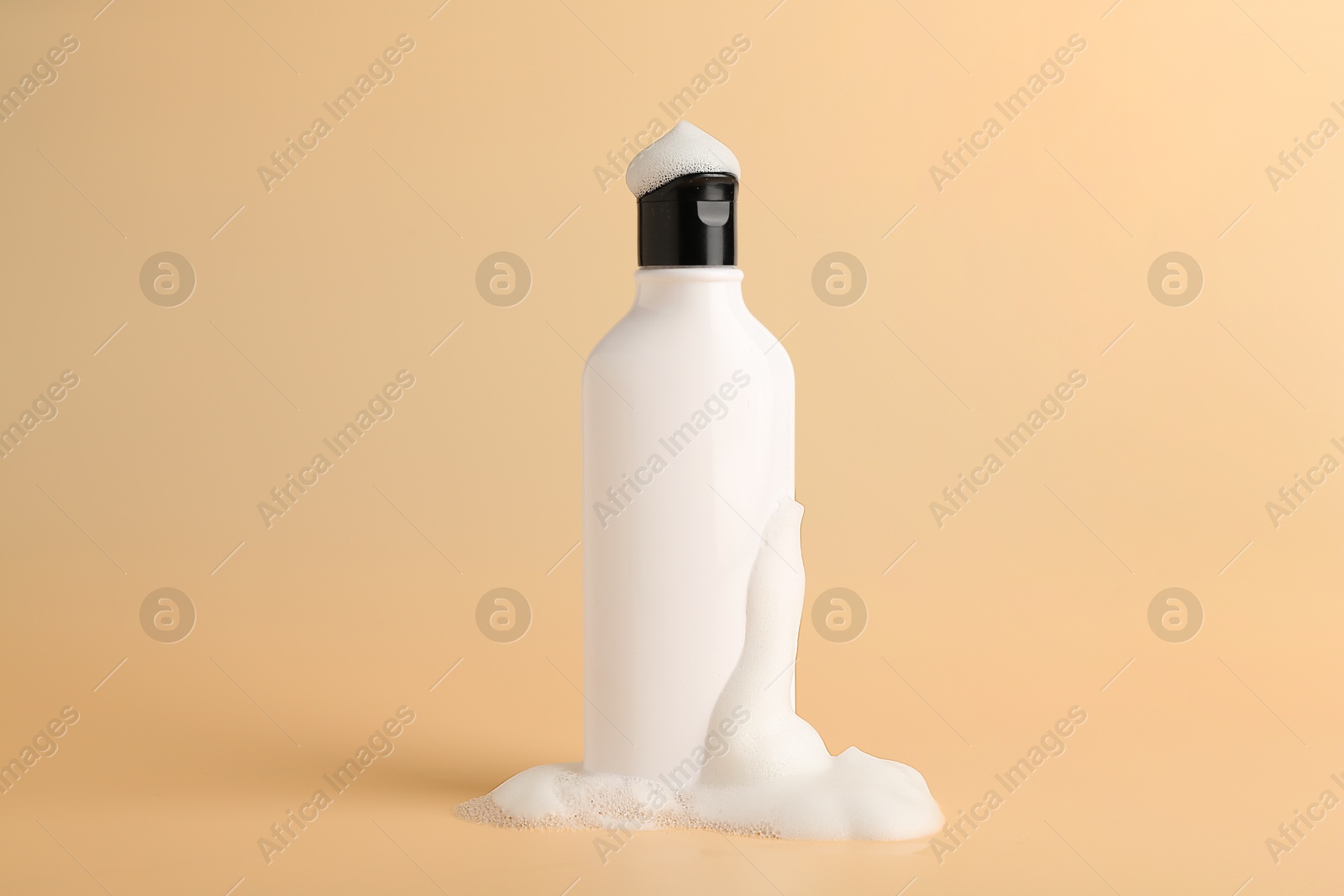 Photo of Bottle of cosmetic product with foam on beige background