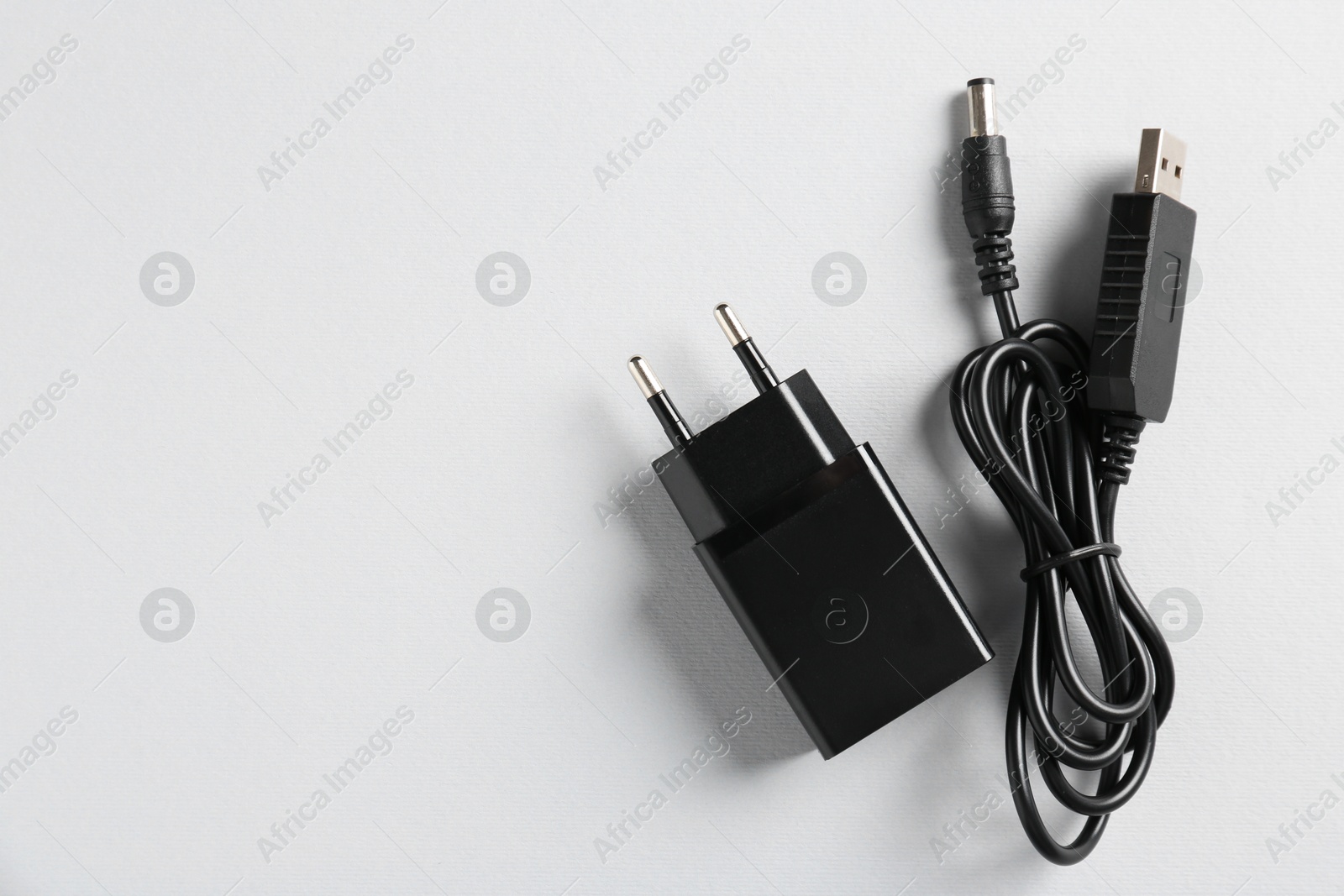 Photo of USB power adapter and charge cable on white background, flat lay. Space for text