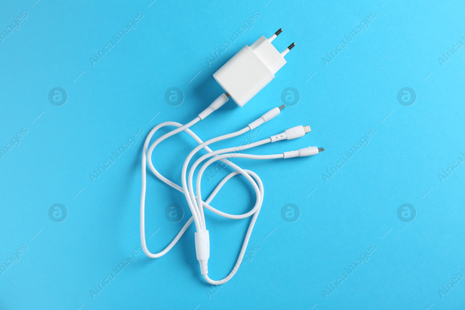 Photo of USB power adapter with triple charge cable on light blue background, top view