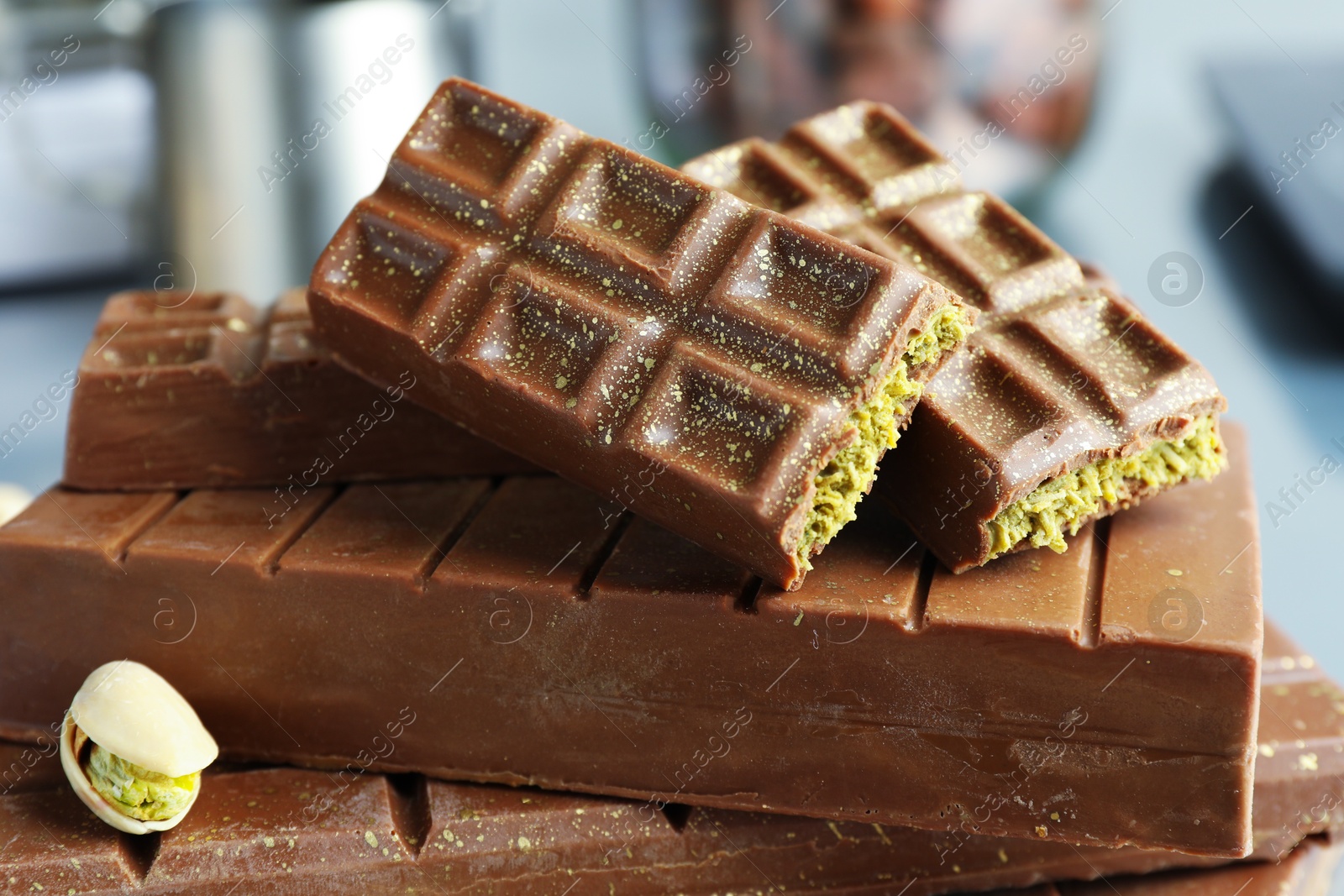 Photo of Stack of tasty Dubai chocolate bars with pistachios and knafeh on blurred background, closeup