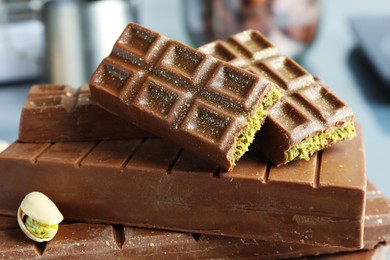 Stack of tasty Dubai chocolate bars with pistachios and knafeh on blurred background, closeup