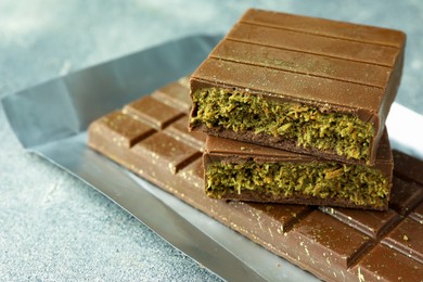 Photo of Tasty Dubai chocolate with pistachios and knafeh on grey textured table, closeup