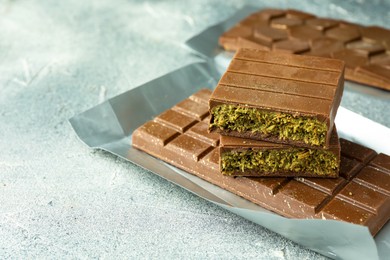 Photo of Tasty Dubai chocolate with pistachios and knafeh on grey textured table, closeup