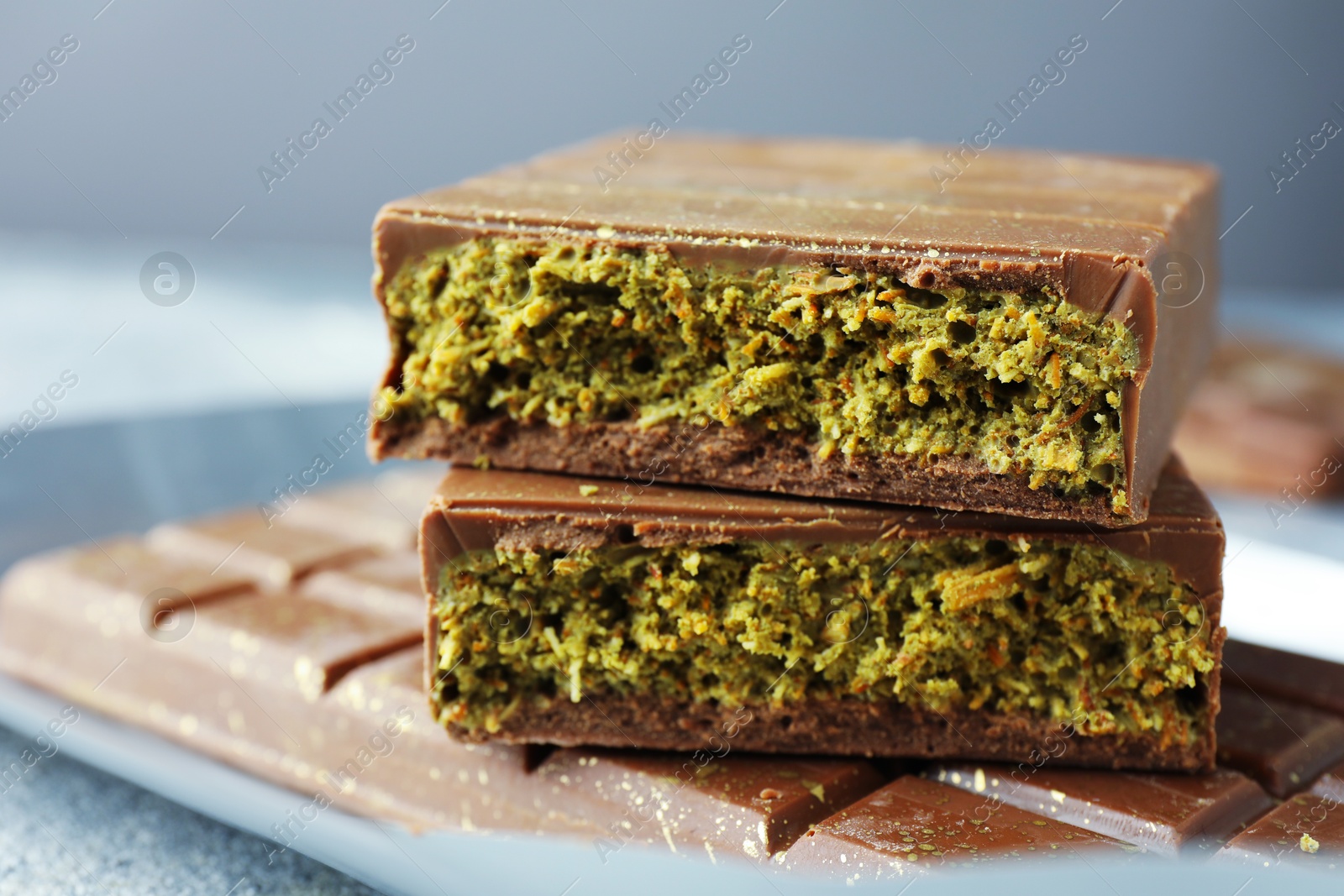 Photo of Tasty Dubai chocolate with pistachios and knafeh on grey table, closeup