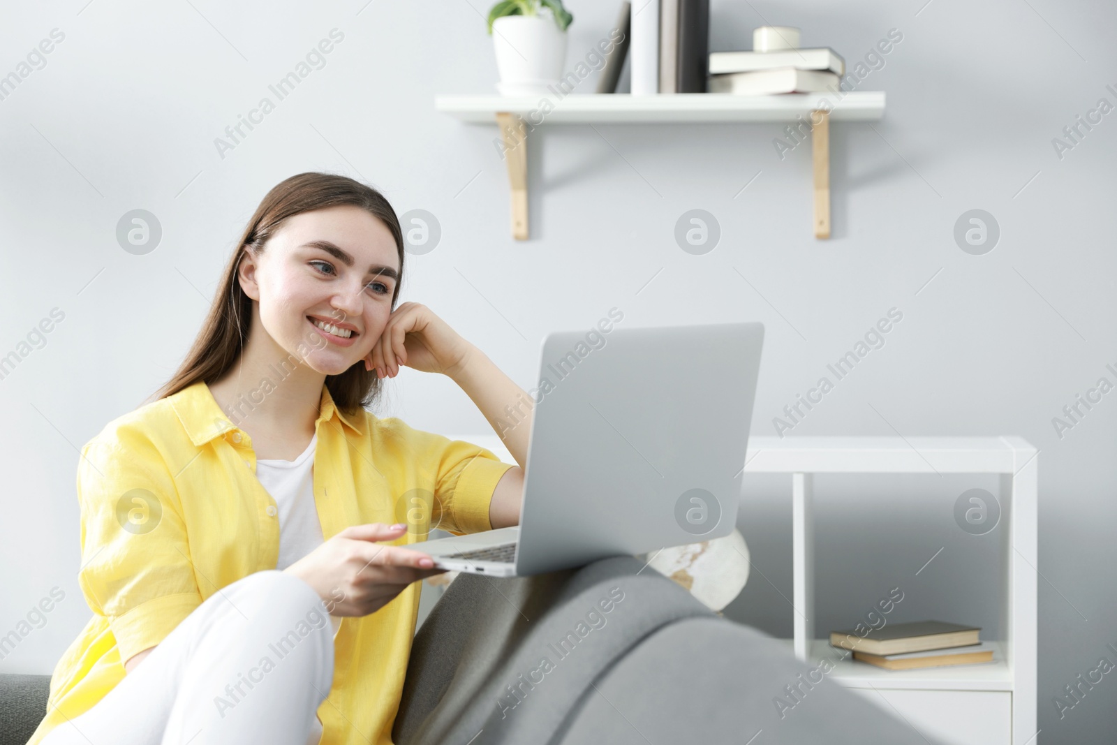 Photo of Young woman using laptop on sofa at home