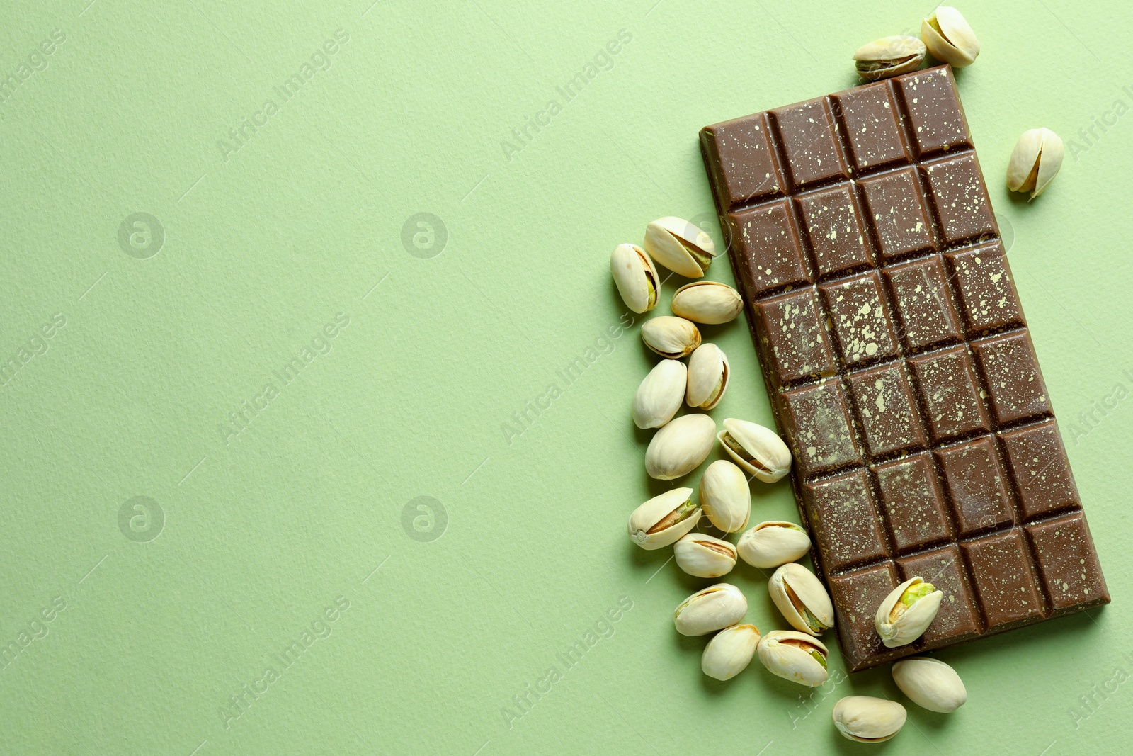 Photo of Delicious Dubai chocolate with pistachios and knafeh on green background, flat lay. Space for text