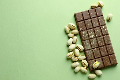 Delicious Dubai chocolate with pistachios and knafeh on green background, flat lay. Space for text