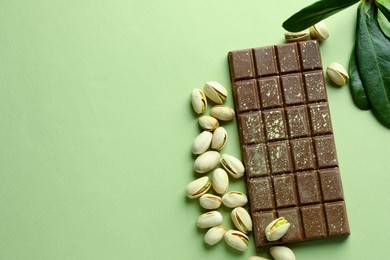 Photo of Delicious Dubai chocolate with pistachios and knafeh on green background, flat lay. Space for text