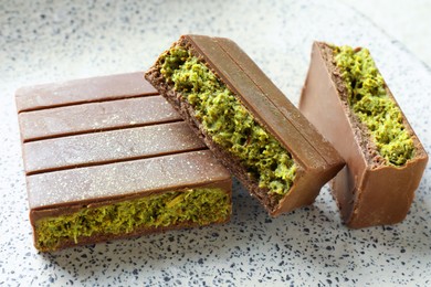 Photo of Pieces of delicious Dubai chocolate with pistachios and knafeh on plate, closeup