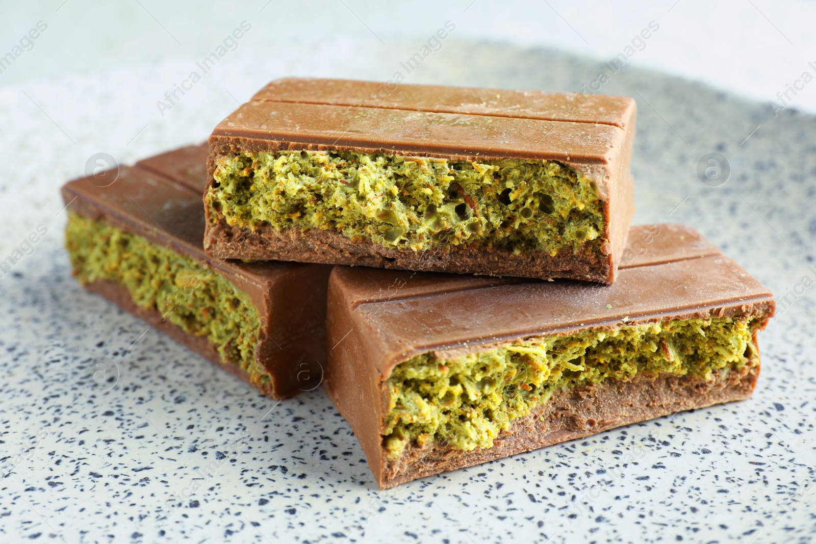 Photo of Pieces of delicious Dubai chocolate with pistachios and knafeh on plate, closeup