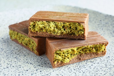 Photo of Pieces of delicious Dubai chocolate with pistachios and knafeh on plate, closeup