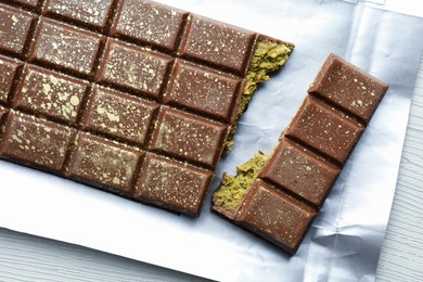 Photo of Delicious Dubai chocolate with pistachios and knafeh on white wooden table, top view