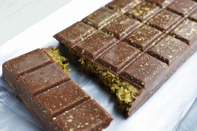 Photo of Delicious Dubai chocolate with pistachios and knafeh on table, closeup