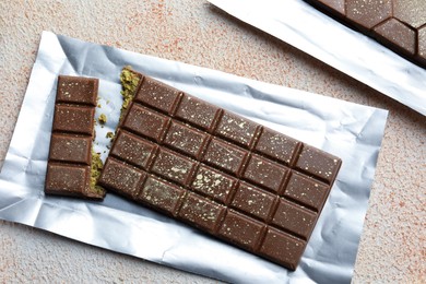 Photo of Delicious Dubai chocolate with pistachios and knafeh on color textured table, top view