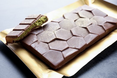 Photo of Delicious Dubai chocolate with pistachios and knafeh on grey table, closeup