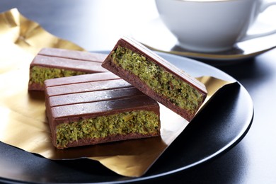 Photo of Pieces of delicious Dubai chocolate with pistachios and knafeh on grey table, closeup