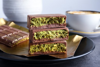 Photo of Pieces of delicious Dubai chocolate with pistachios and knafeh on grey table, closeup