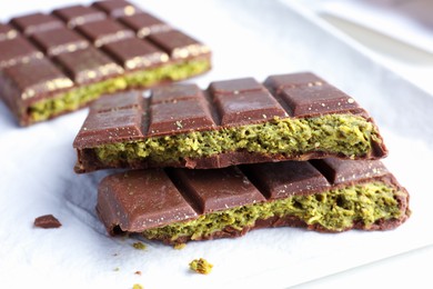 Photo of Pieces of delicious Dubai chocolate with pistachios and knafeh on table, closeup