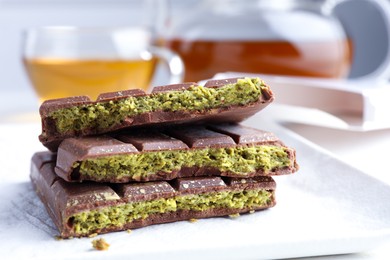 Photo of Pieces of delicious Dubai chocolate with pistachios and knafeh on table, closeup