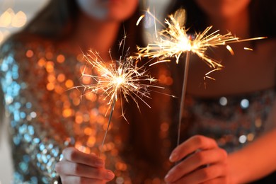 Photo of Women with bright burning sparklers, selective focus