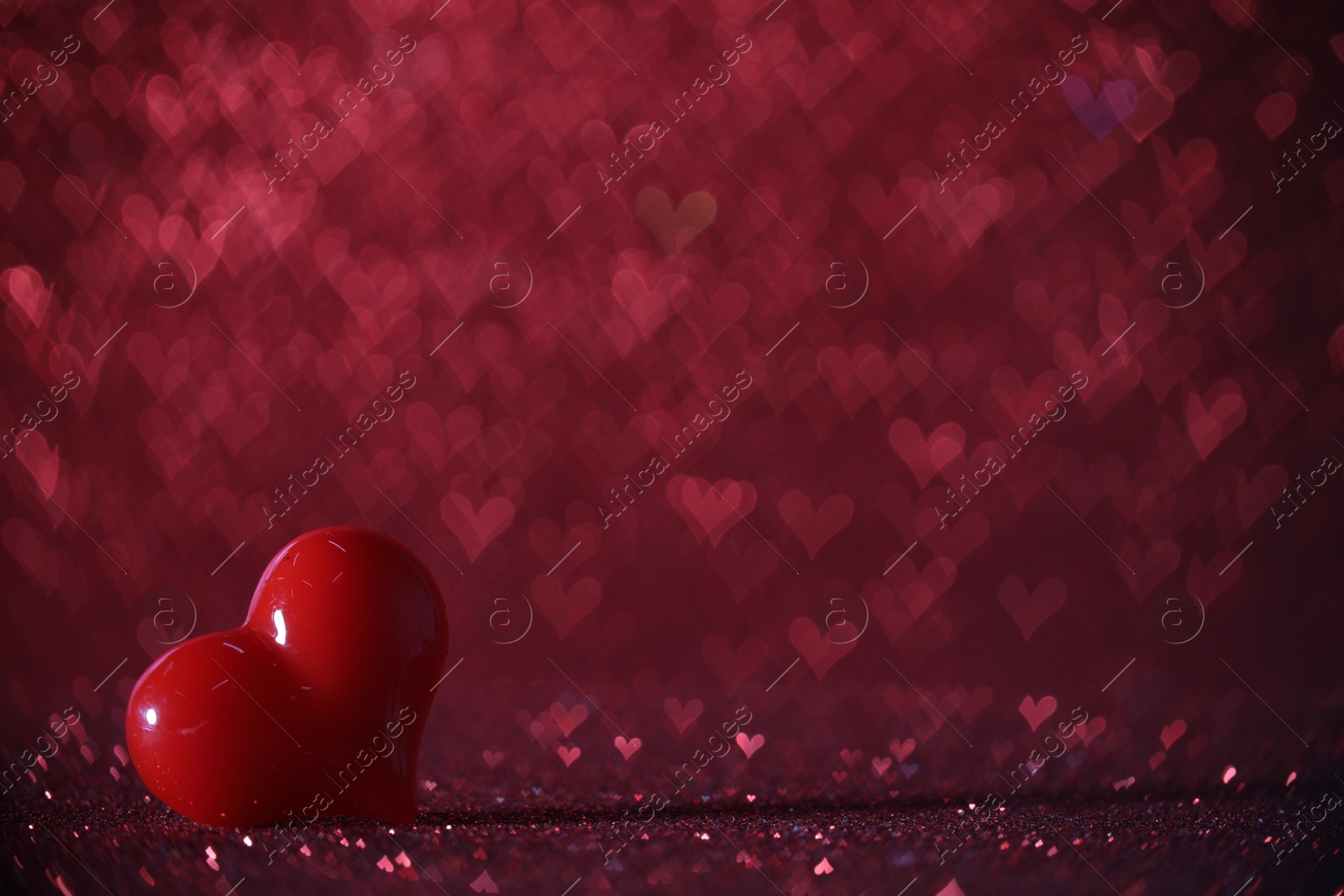 Photo of Romantic decor. Small heart on shiny pink glitter and bokeh lights, space for text