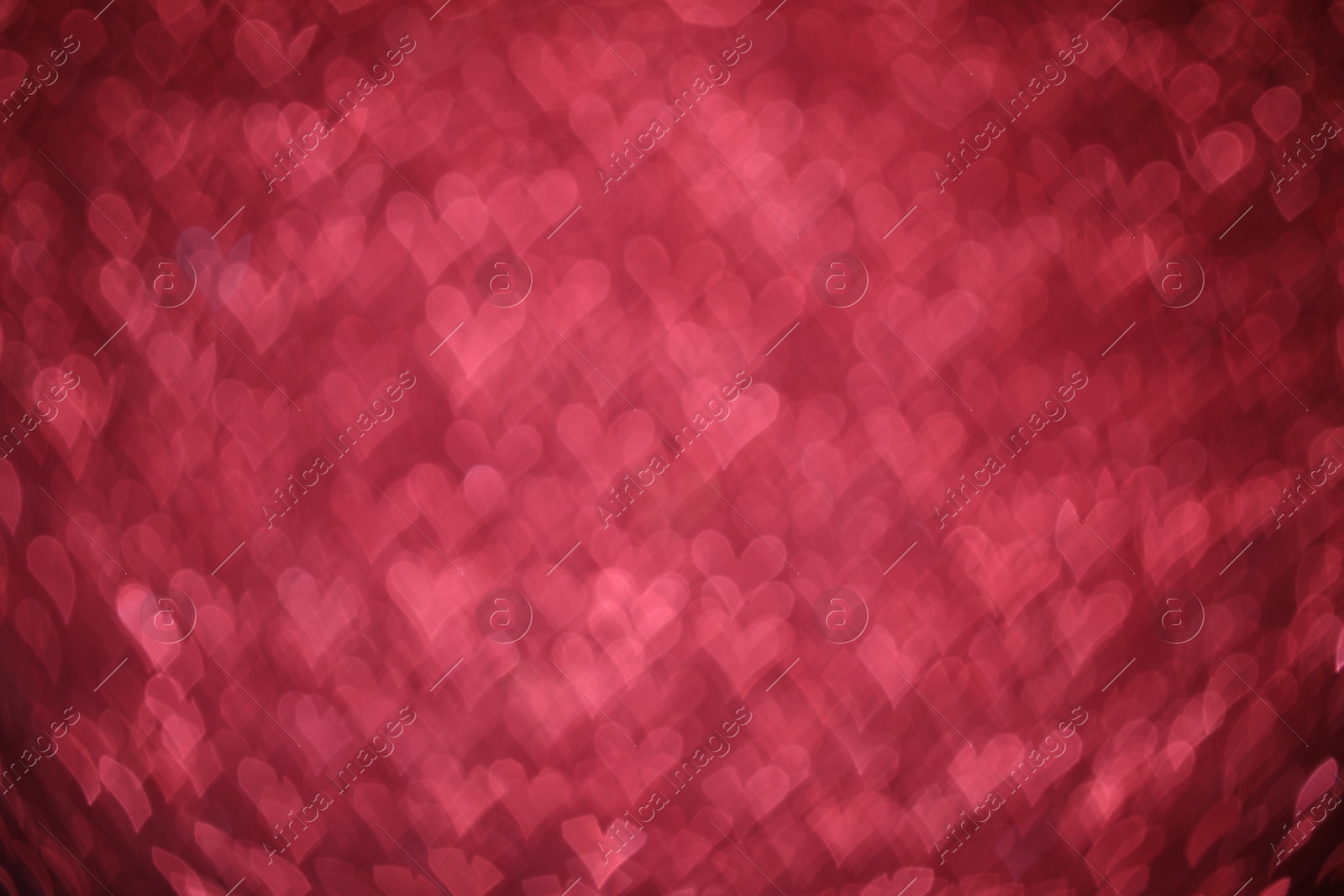 Photo of Romantic decor. Blurred view of heart shaped lights on pink background, bokeh effect