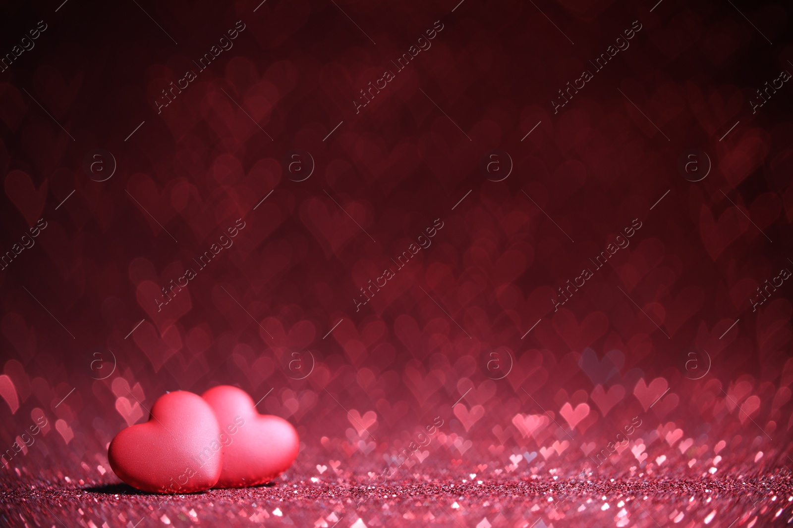 Photo of Romantic decor. Small hearts on shiny pink glitter and heart shaped lights, space for text. Bokeh effect